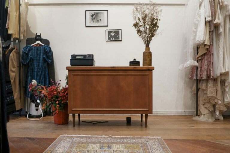 Houten toonbank met bloemen, vintage jurk en droogboeket in vintage kledingwinkel