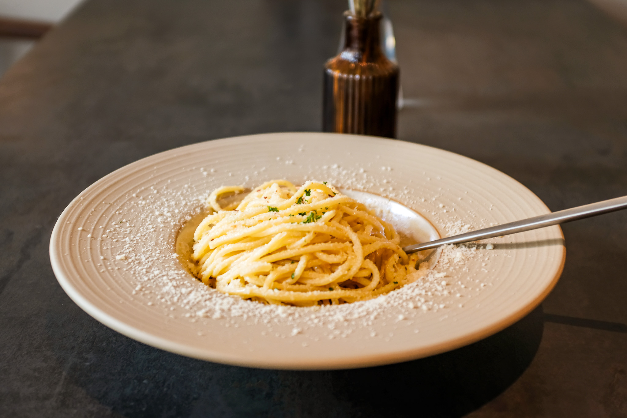 Een bord spaghetti aglio olio bij restaurant Amici aan de Astraat in Groningen, met knoflook, olijfolie en Parmezaanse kaas.